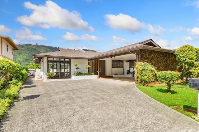 view of front of house with stone siding, a mountain view, driveway, and stucco siding