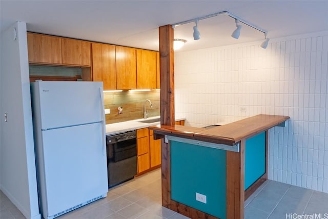 kitchen featuring sink, black dishwasher, track lighting, kitchen peninsula, and white fridge