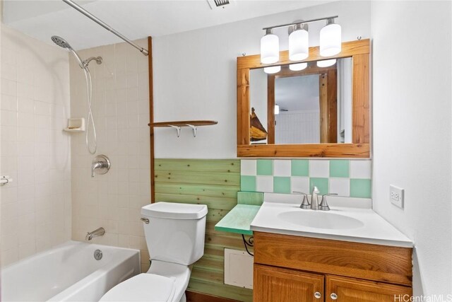 full bathroom featuring vanity, backsplash, tiled shower / bath combo, and toilet