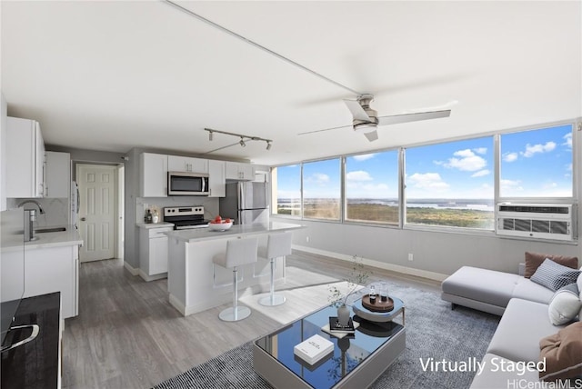 living room featuring wood-type flooring, sink, cooling unit, and ceiling fan