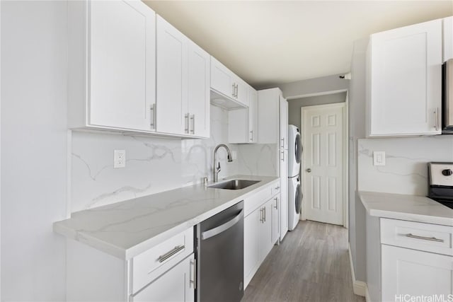 kitchen featuring stacked washer and clothes dryer, sink, tasteful backsplash, stainless steel dishwasher, and white cabinets