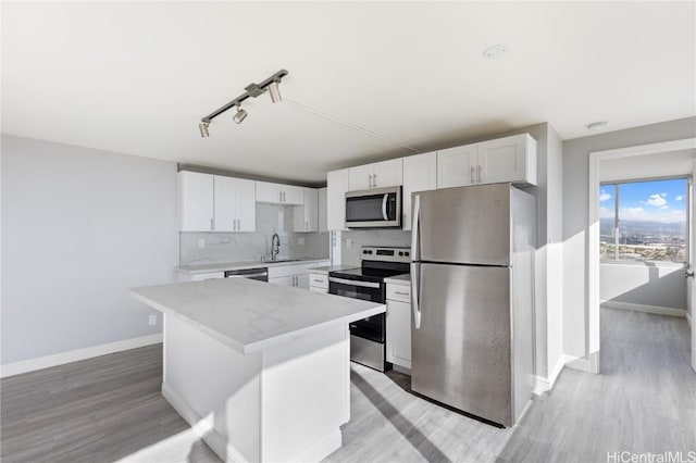 kitchen with a kitchen island, appliances with stainless steel finishes, tasteful backsplash, sink, and white cabinets