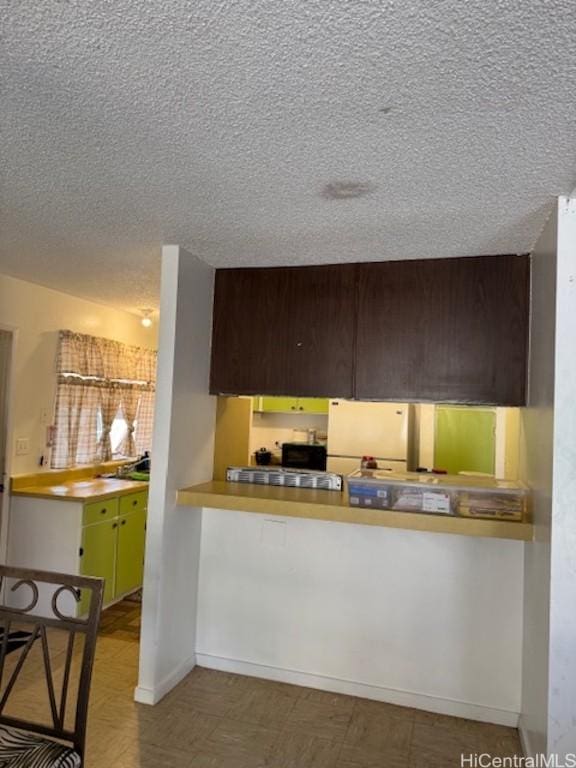 kitchen featuring kitchen peninsula, dark brown cabinets, and white fridge