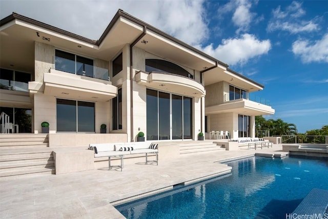 rear view of property featuring a fenced in pool and a patio