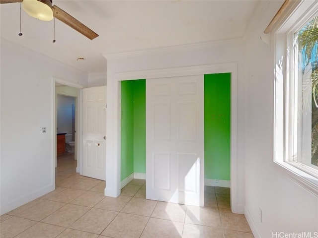 unfurnished bedroom featuring ceiling fan, light tile patterned floors, and ornamental molding