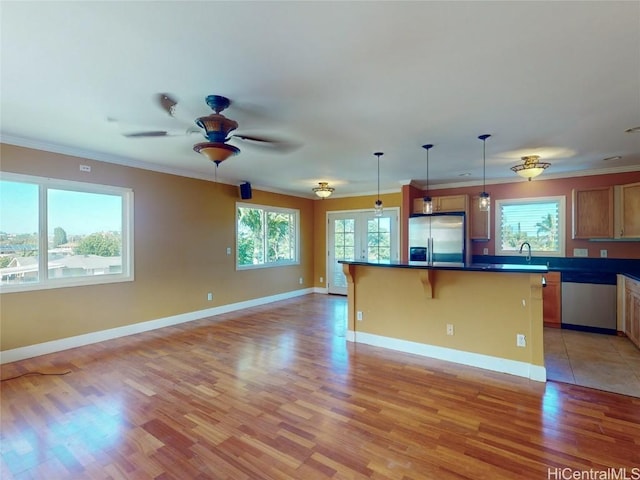 kitchen featuring a breakfast bar, a center island, stainless steel refrigerator with ice dispenser, hanging light fixtures, and light wood-type flooring