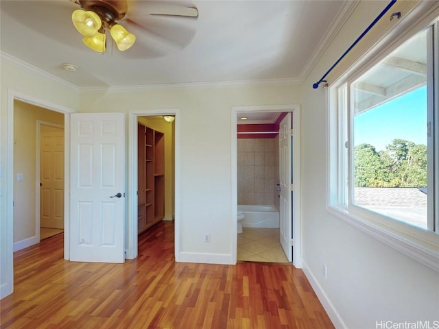 unfurnished bedroom featuring a walk in closet, connected bathroom, multiple windows, and ceiling fan