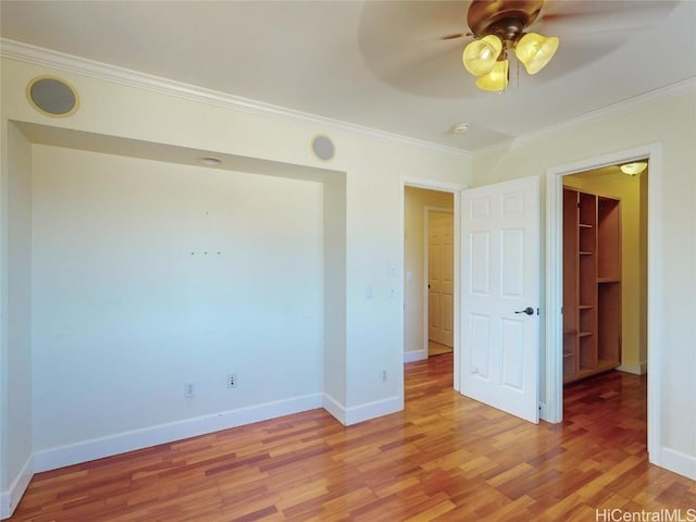 unfurnished bedroom with ceiling fan, a spacious closet, light hardwood / wood-style floors, a closet, and ornamental molding