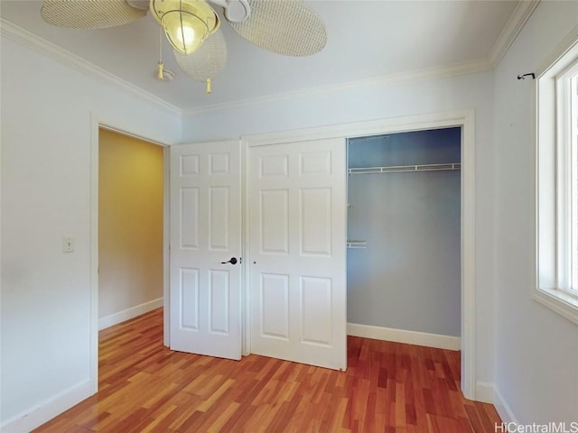 unfurnished bedroom with ceiling fan, a closet, wood-type flooring, and ornamental molding