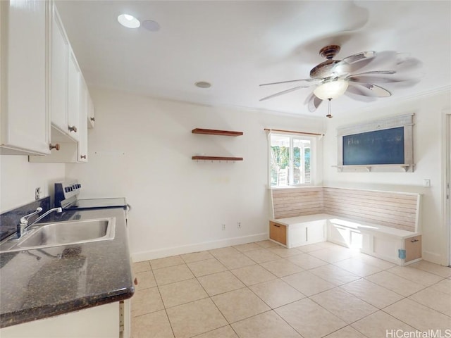 kitchen with ceiling fan, sink, light tile patterned flooring, dark stone counters, and white cabinets