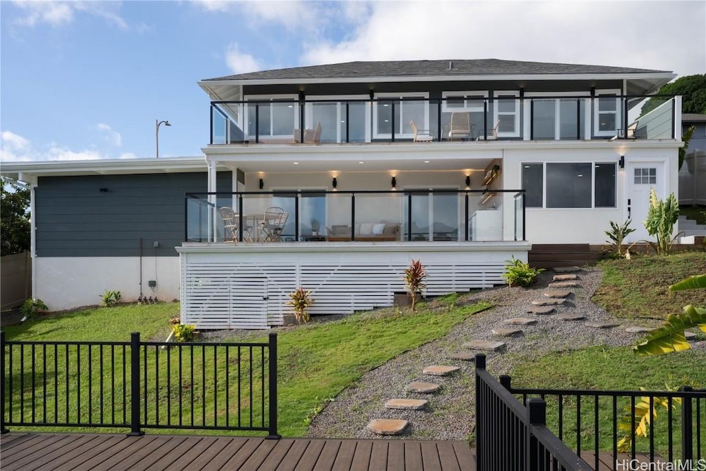 rear view of house featuring a balcony and a yard