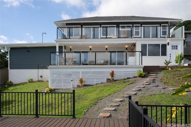 rear view of house featuring a balcony and a yard