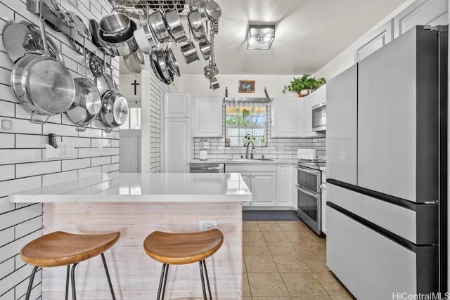 kitchen featuring sink, a kitchen bar, white cabinetry, and stainless steel appliances