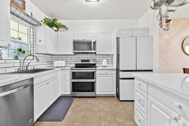 kitchen with white cabinetry, sink, stainless steel appliances, tasteful backsplash, and light tile patterned floors