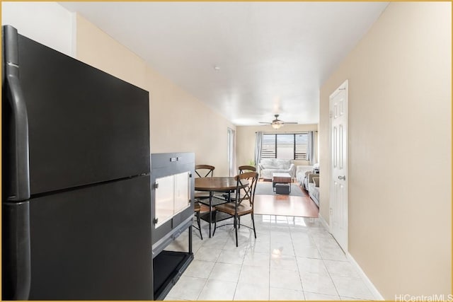 kitchen featuring light tile patterned flooring, black refrigerator, and ceiling fan