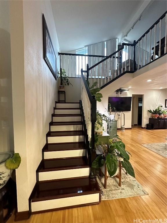 stairs featuring hardwood / wood-style floors and a high ceiling