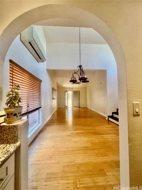 hallway with a wealth of natural light, a wall mounted AC, and light hardwood / wood-style floors