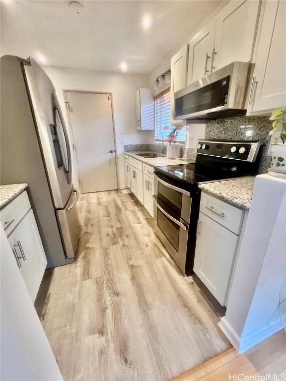 kitchen with white cabinetry, appliances with stainless steel finishes, light hardwood / wood-style floors, and sink