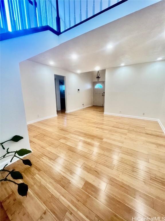 unfurnished living room with a towering ceiling and light wood-type flooring