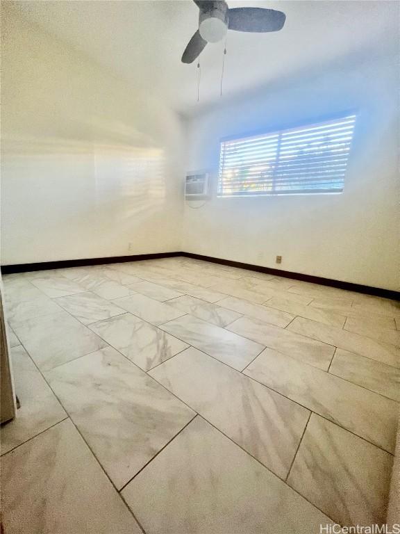 spare room featuring ceiling fan and an AC wall unit