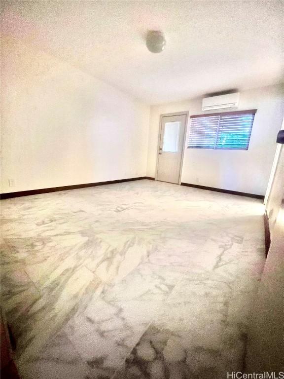 unfurnished room featuring carpet, a wall mounted AC, and a textured ceiling