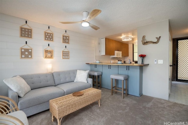 carpeted living room with ceiling fan and a textured ceiling