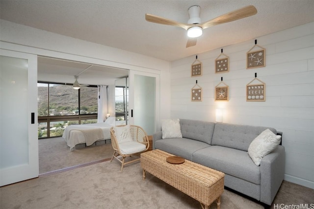 living room with a textured ceiling, light colored carpet, and ceiling fan