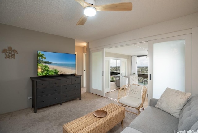 living room with light carpet, a textured ceiling, and ceiling fan