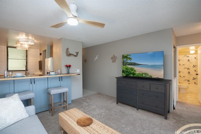 carpeted living room with a textured ceiling, ceiling fan, and sink