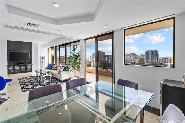 tiled dining space featuring floor to ceiling windows and a raised ceiling