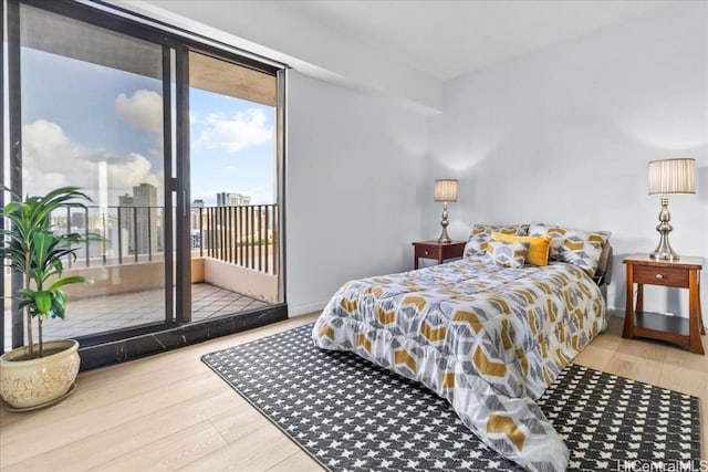 bedroom with access to exterior, hardwood / wood-style flooring, and expansive windows