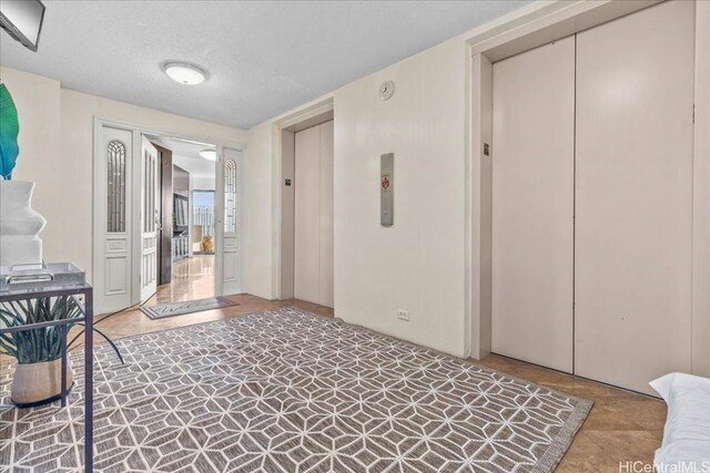 hall with elevator and a textured ceiling