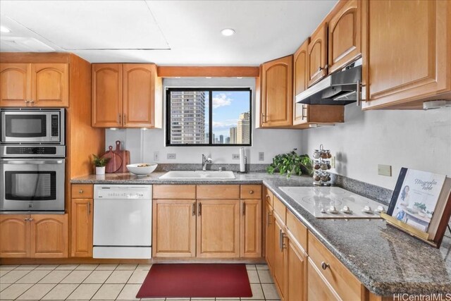 kitchen featuring sink, stainless steel appliances, dark stone counters, and light tile patterned floors