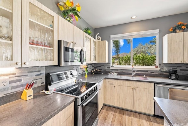 kitchen with sink, light brown cabinets, stainless steel appliances, light hardwood / wood-style flooring, and decorative backsplash