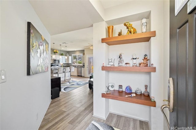 interior space with pendant lighting, ceiling fan, light hardwood / wood-style flooring, and stainless steel appliances