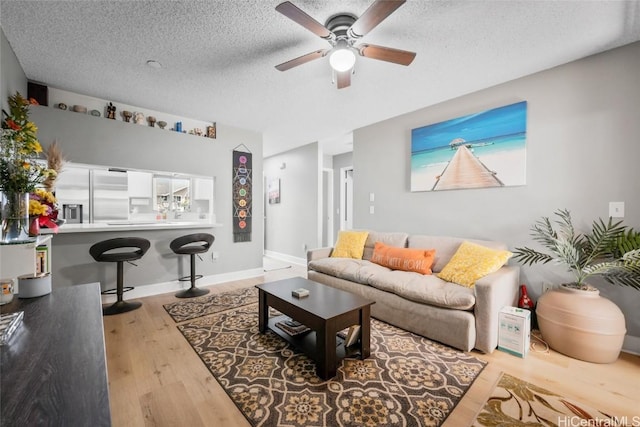 living room featuring a textured ceiling, light hardwood / wood-style floors, and ceiling fan