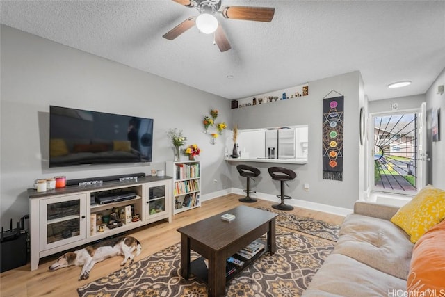 living room featuring ceiling fan, light hardwood / wood-style floors, and a textured ceiling