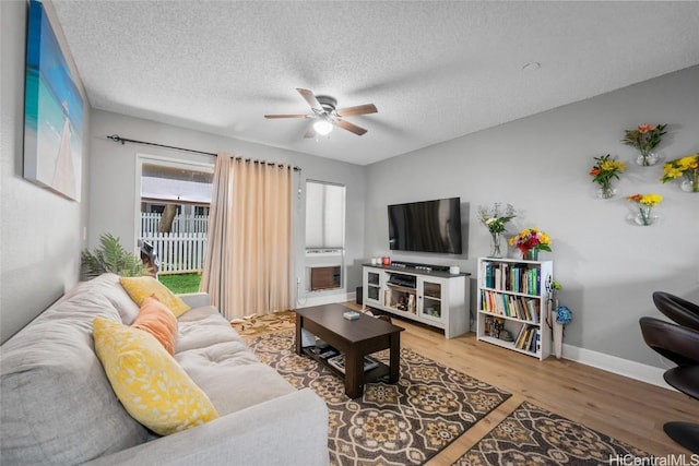 living room featuring ceiling fan, wood-type flooring, and a textured ceiling