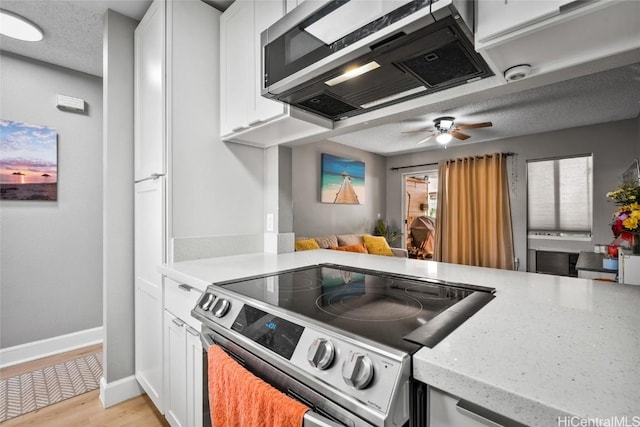 kitchen featuring white cabinets, light wood-type flooring, stainless steel appliances, and a textured ceiling