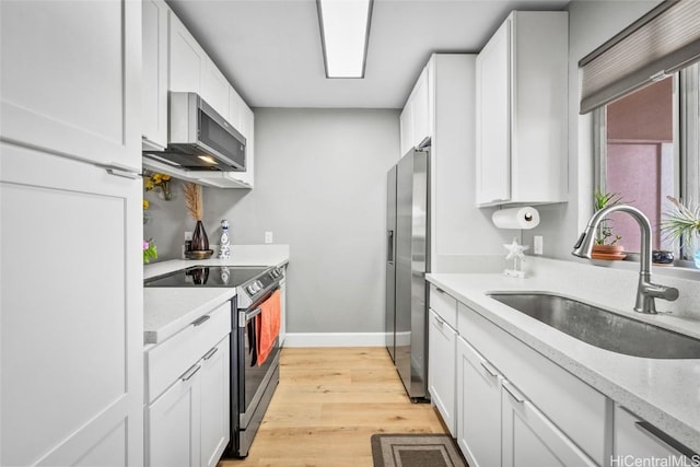 kitchen featuring white cabinets, stainless steel appliances, light stone counters, and sink