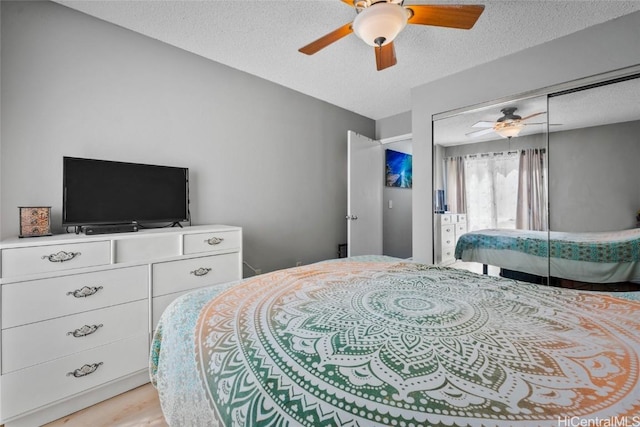 bedroom with ceiling fan, light hardwood / wood-style flooring, a textured ceiling, and a closet