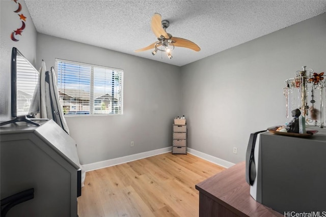 office area with ceiling fan, light wood-type flooring, and a textured ceiling