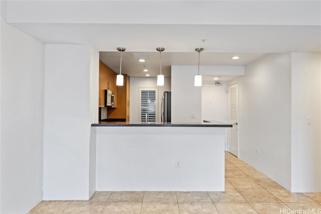 kitchen with kitchen peninsula, appliances with stainless steel finishes, pendant lighting, light tile patterned floors, and dark stone countertops