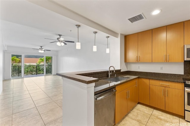 kitchen with ceiling fan, sink, stainless steel appliances, kitchen peninsula, and dark stone counters