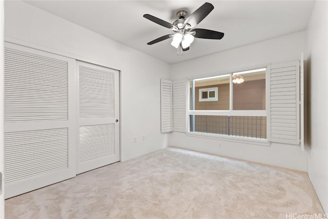 unfurnished bedroom featuring light carpet, a closet, and ceiling fan