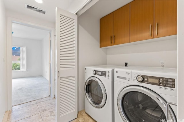 laundry area with light tile patterned floors, washing machine and dryer, light colored carpet, visible vents, and cabinet space