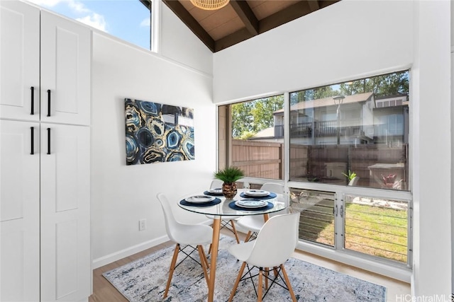 dining space featuring plenty of natural light, wood-type flooring, and lofted ceiling with beams