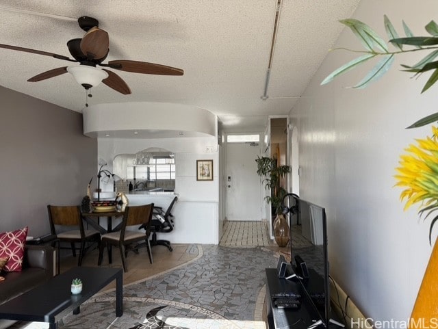 living room featuring ceiling fan and a textured ceiling