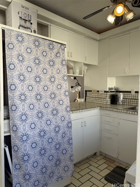 kitchen with white cabinets, decorative backsplash, and tile counters