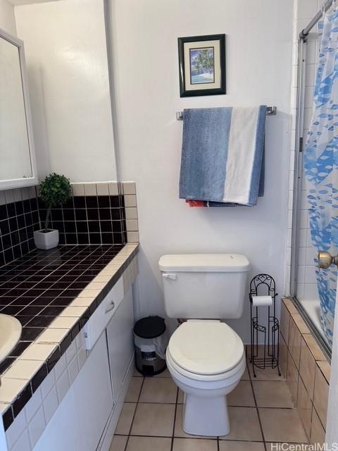 bathroom featuring tile patterned flooring, toilet, and tub / shower combination